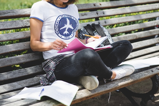 Photo gratuite fille assise sur banc en parc en train d'étudier