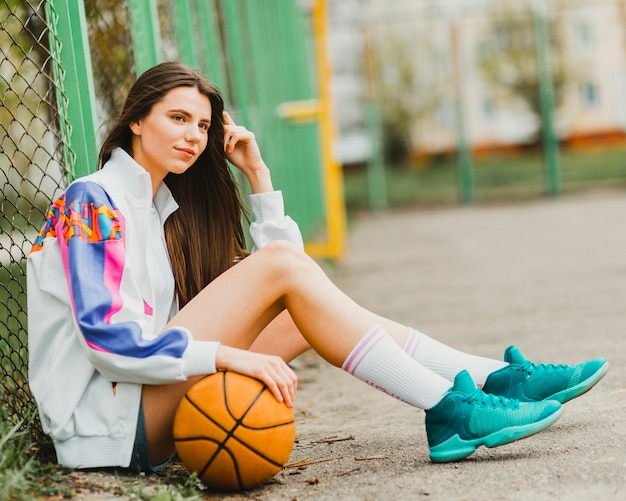 Photo gratuite fille assise avec le basket-ball