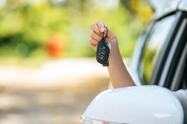 Fille assise dans la voiture et tenant les mains des clés de la voiture hors de la voiture.