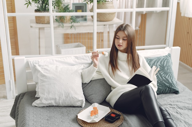 Fille assise à la maison sur un canapé avec un sushi