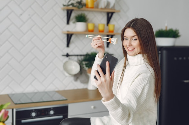 Fille assise à la maison à la table avec un sushi