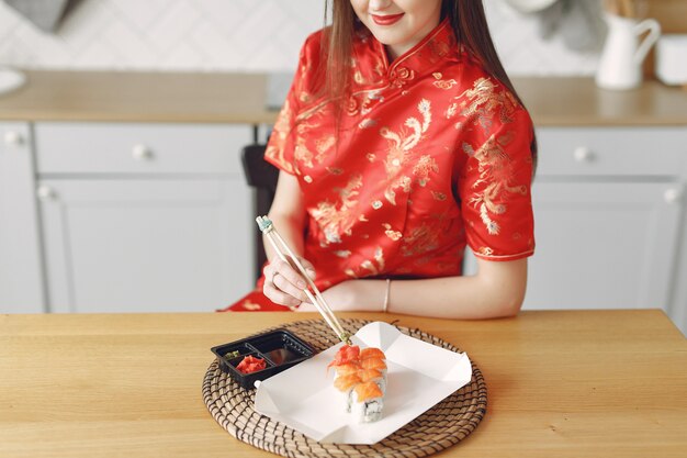 Fille assise à la maison à la table avec un sushi