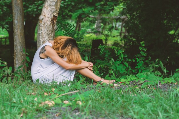 Fille assise sur le sol avec sa tête contre ses genoux