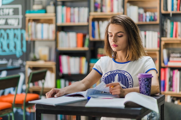 Fille assise à table avec des cahiers à l&#39;étude