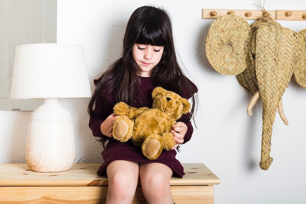 Fille assise sur une table avec peluche