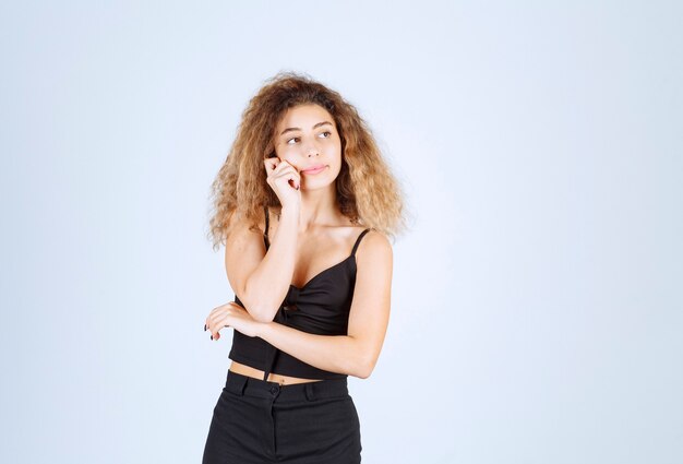 Fille aux cheveux bouclés donnant des poses méchantes et positives.