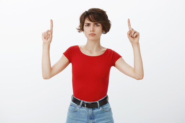 Une fille aux cheveux courts posant dans un t-shirt rouge