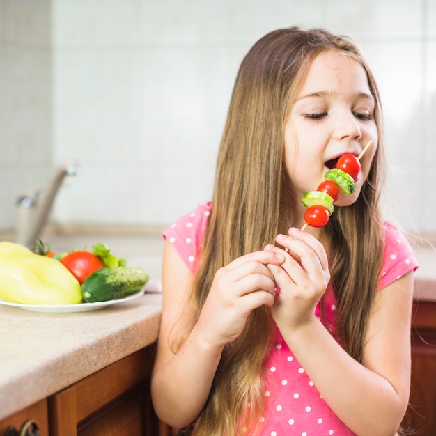 Fille aux cheveux longs, manger une brochette de salade