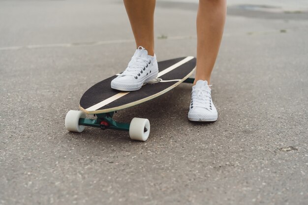 fille aux cheveux longs patins sur une planche à roulettes. rue, sports actifs