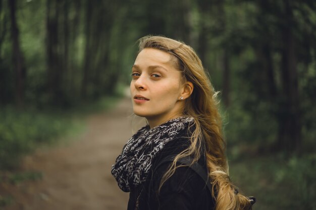 fille aux cheveux longs se promène dans la forêt.