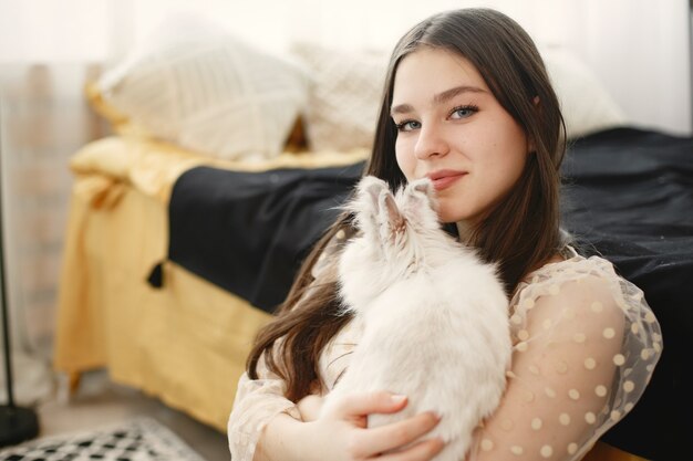 Fille aux cheveux longs tenant un lapin blanc.