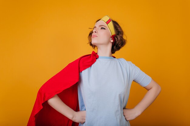 Fille aux cheveux noirs en t-shirt bleu debout dans une pose confiante et à l'écart