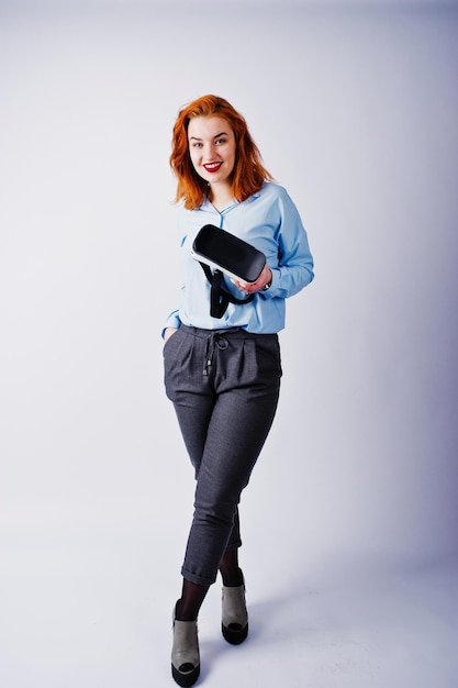 Fille aux cheveux rouges en blouse bleue avec des lunettes vr au studio isolé sur blanc