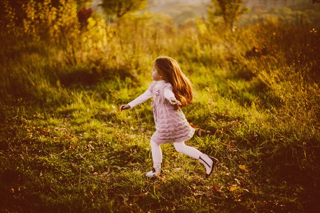 Fille aux cheveux roux marche sur les feuilles mortes