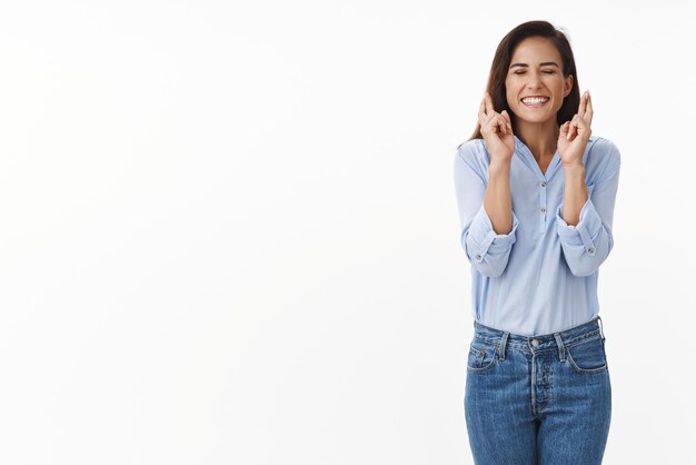 Fille avoir de la chance bonne fortune Femme adulte optimiste avec tatouage fermer les yeux souriant largement anticipant le rêve devenu réalité miracle résultats positifs croiser les doigts priant fond blanc