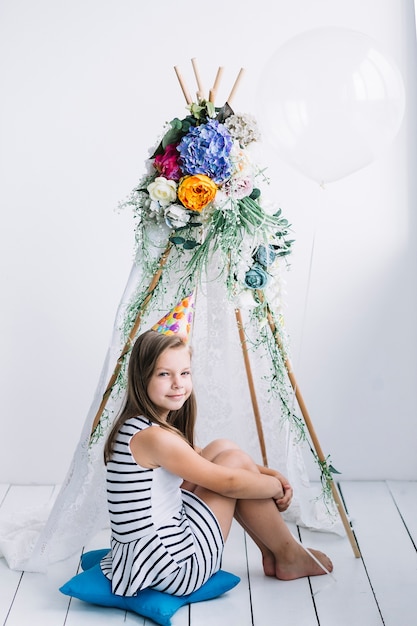 Fille avec ballon assis près de la tente pour la fête d'anniversaire