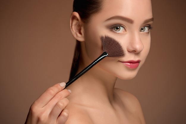 Fille de beauté avec pinceau de maquillage. Peau parfaite. Appliquer le maquillage