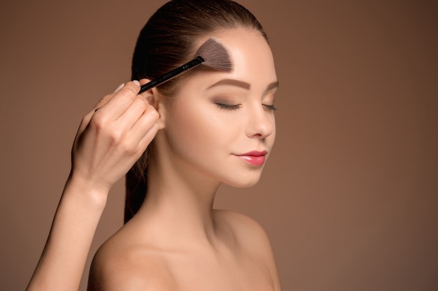 Fille de beauté avec pinceau de maquillage. Peau parfaite. Maquillage