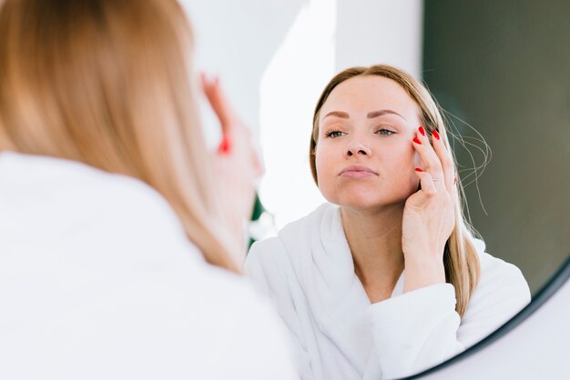 Fille blonde en appliquant la crème sur son visage