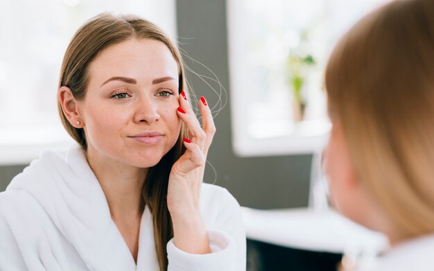 Fille blonde en appliquant la crème sur son visage