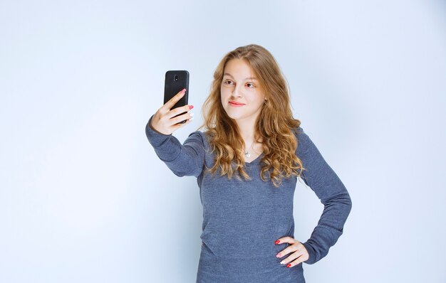 Fille blonde aux cheveux bouclés prenant son selfie.