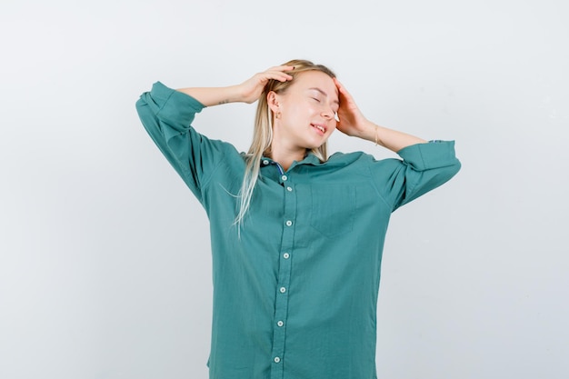 Fille Blonde En Chemisier Vert Mettant Les Mains Sur La Tête, Fermant Les Yeux Et L'air Calme