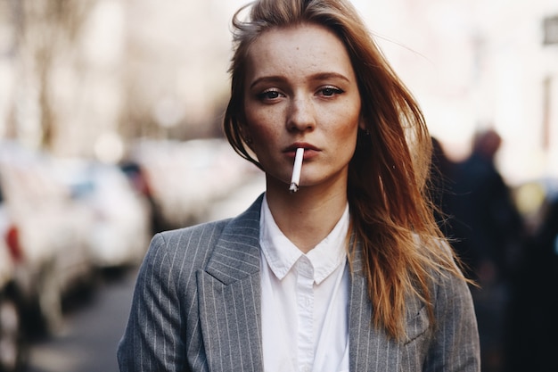 Fille blonde avec des cigares se trouve dans la rue