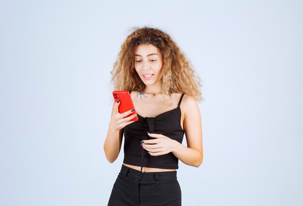 Fille blonde discutant avec son téléphone et se sentant positive.