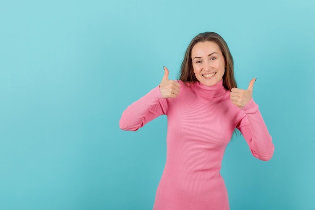 Une fille blonde heureuse montre des gestes parfaits en levant les pouces sur fond bleu