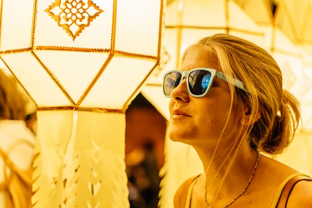 Fille blonde avec des lunettes de soleil entourée de lanternes chinoises dans la nuit