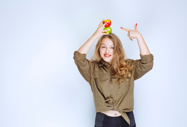 Fille blonde mettant une pêche rouge sur sa tête.