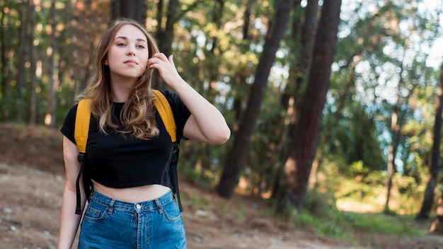 Fille blonde à mi-tir avec sac à dos en forêt