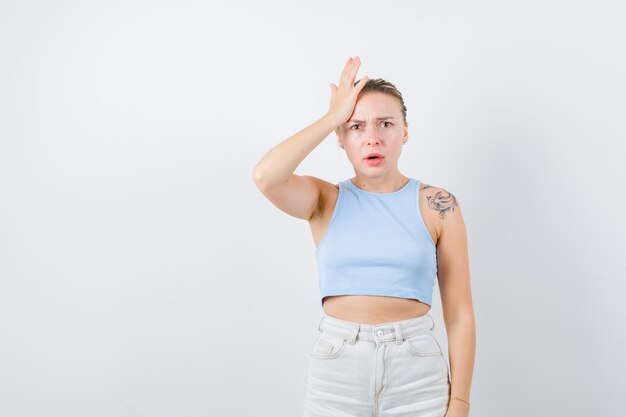 La fille blonde montre sa tête sur le fond blanc