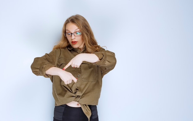 Fille blonde pointant sur sa montre et vérifiant l'heure.