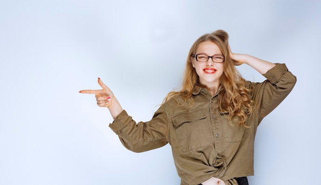 Fille blonde pointant vers quelqu'un sur la gauche.