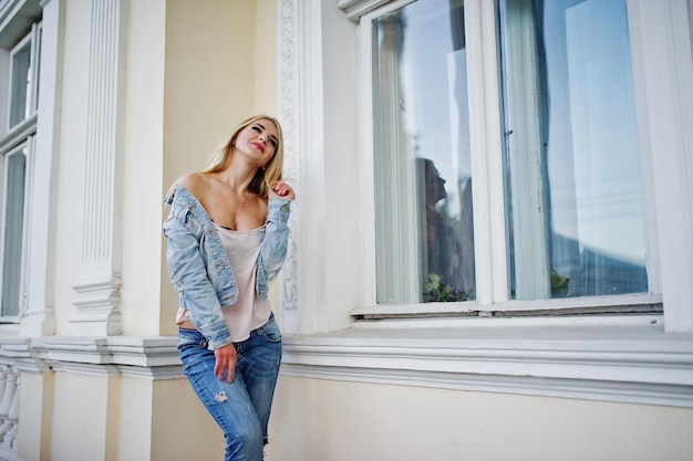 Fille blonde porter des jeans posés contre la vieille maison