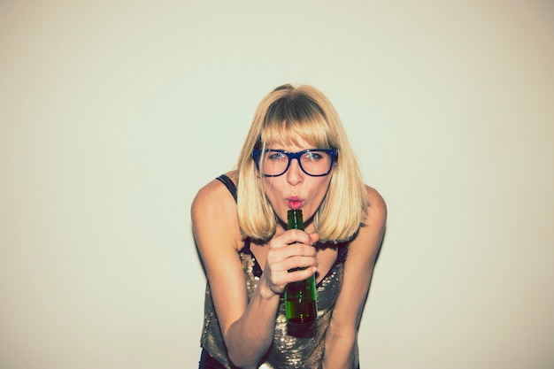 Fille blonde posant avec une bière