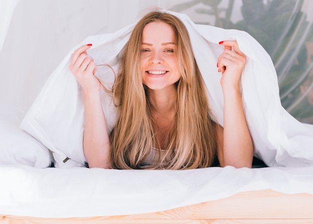 Fille blonde posant sur le lit