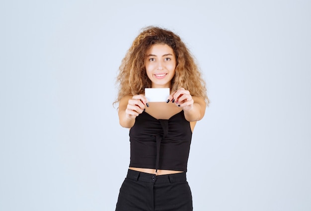 Fille blonde présentant ou recevant une carte de visite en toute confiance.