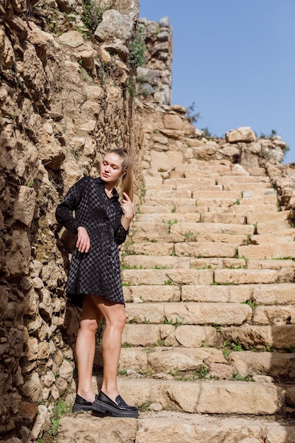 La fille blonde regarde à gauche en robe noire sur fond de pierre