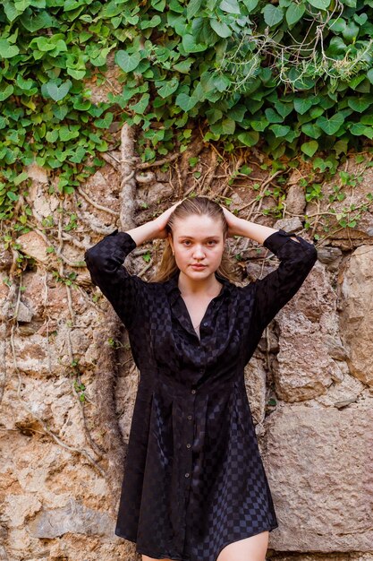 La fille blonde regarde à gauche en robe noire sur fond de pierre