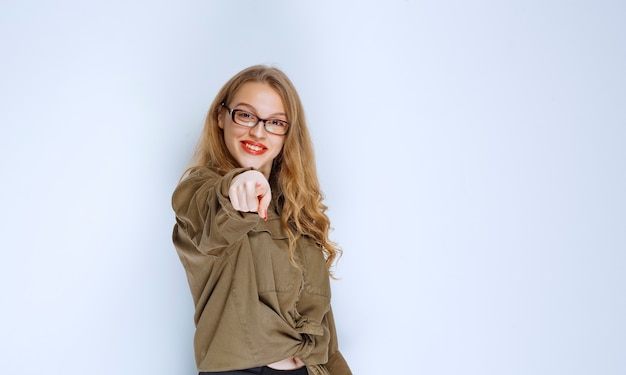 Fille blonde remarquant et pointant vers la personne devant.