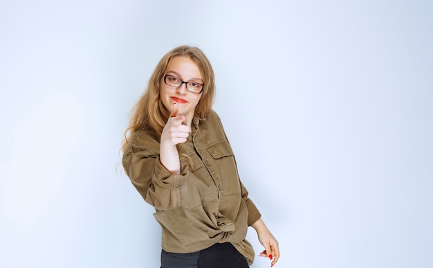 Fille blonde remarquant et pointant vers la personne devant.