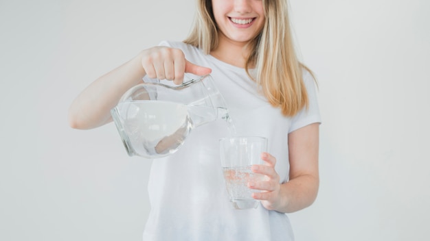 Fille blonde remplissant un verre d&#39;eau