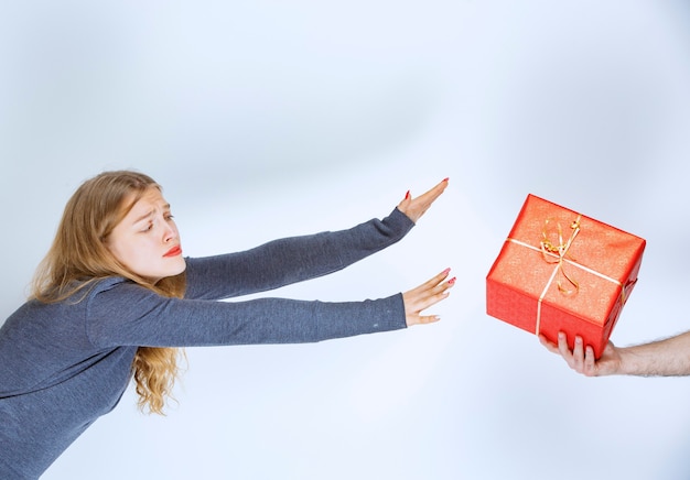 Une fille blonde se voit offrir un coffret cadeau rouge et elle a hâte de le prendre.