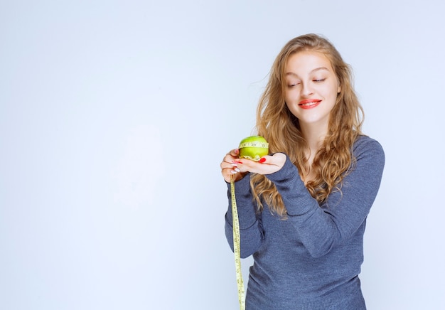 Fille blonde tenant une pomme verte dans ses paumes.