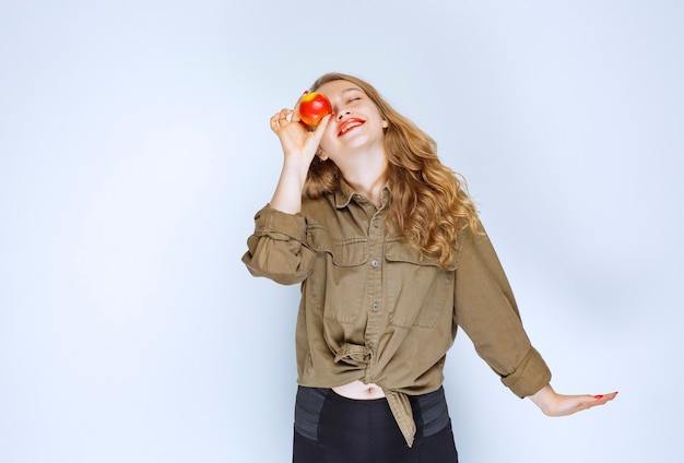 Photo gratuite fille blonde tenant et promouvant une pêche rouge.