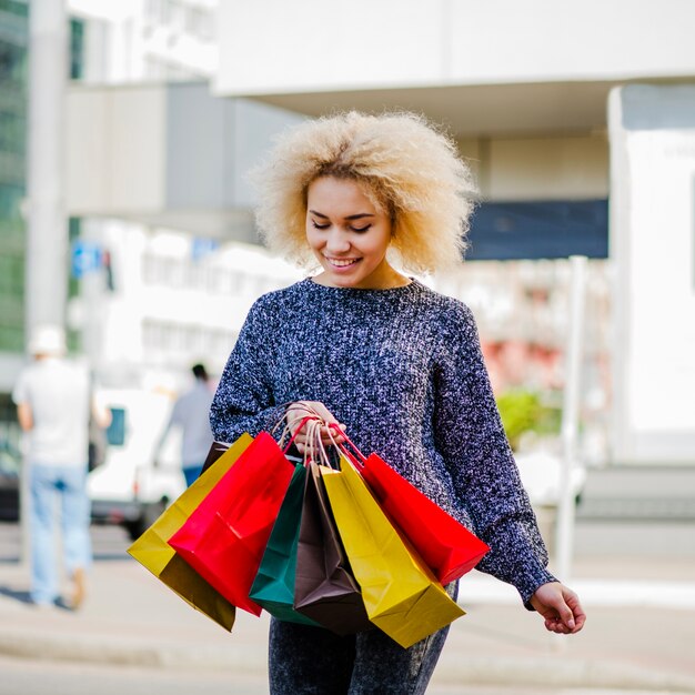 Fille blonde tenant des sacs à provisions en marche