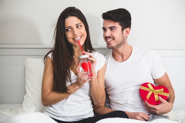 Fille de boire dans une tasse avec un coeur et son petit ami avec une boîte en forme de coeur