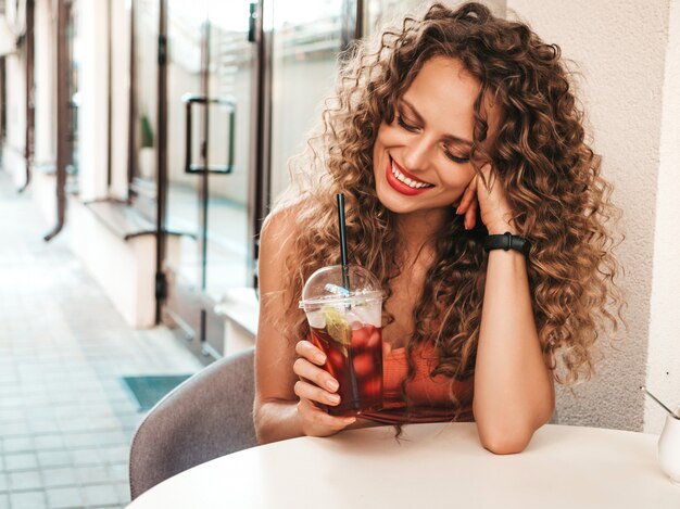 Fille de boire un smoothie frais dans une tasse en plastique avec de la paille